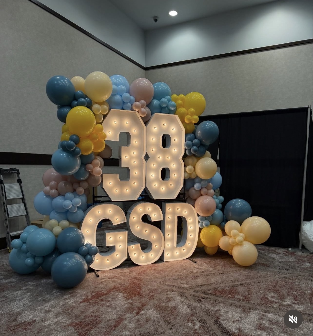 Balloon garland framing a lit marquee display at a corporate event